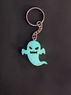 a keychain with a blue ghost on it's side and a black background