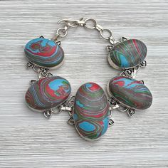 Vintage panel bracelet that is testing positive for silver but is not signed so I think this is silver plated. The stones are multi colored.  The bracelet is adjustable with a toggle style clasp.  Please contact us if you have any questions.  Bracelet is adjustable down by 1 1/2 inches so maximum length of 9 inches and minimum length of 7 1/2 inches.  To view our vintage bracelet section click on the link below https://www.etsy.com/shop/WhyWeLoveThePast?ref=hdr_shop_menu&section_id=14681809 Plea Recycled Bracelets, Vintage Hat Boxes, 1970s Jewelry, Large Bracelet, Chunky Bracelet, Antique Bracelets, Chunky Bracelets, Vintage Bracelet, Bracelet Vintage