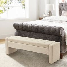 a bedroom with a large bed and a bench on the floor in front of it