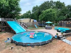 an above ground pool with a slide in the middle and children's play area behind it