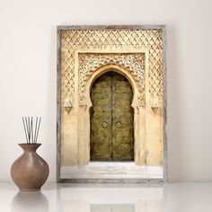 a vase sitting next to a door on a white surface with a mirror behind it