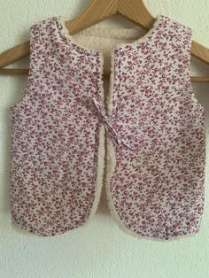 a pink and white floral vest hanging on a wall