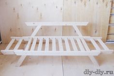 a white wooden bench sitting on top of a hard wood floor next to a wall