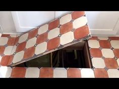 an open window on the side of a wall with red and white tiles in it