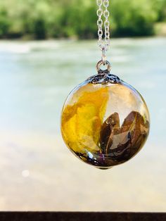 This is a handcrafted yellow flower terrarium resin bubble necklace! I created this pendant with a yellow dried wildflower, tree pieces, and real moss. This will make a great addition to your collection or as a special gift. This pendant includes an 18- or 20-inch sterling silver plated chain or a 20-inch stainless 20-inch chain! (Please choose your chain choice at checkout) Gift ideas include (Mother's Day gift, bridal shower gift, bridesmaid jewelry, Valentine's Day gift, birthday gifts, grand Resin Necklace With Natural Inclusions, Nature-inspired Resin Necklaces With Round Pendant, Nature-inspired Resin Necklace With Round Pendant, Nature-inspired Resin Round Pendant Necklaces, Nature-inspired Resin Round Pendant Necklace, Nature-inspired Yellow Necklace For Gifts, Yellow Nature-inspired Necklace For Gifts, Flower Terrarium, Epoxy Resin Necklace