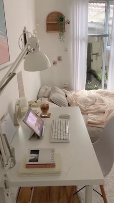 a desk with a laptop, keyboard and mouse on it next to a window in a bedroom