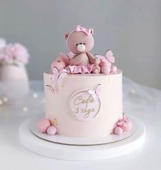 a pink cake with a teddy bear on top