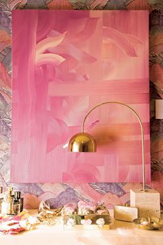 a pink painting is on the wall next to a lamp and other items in front of it