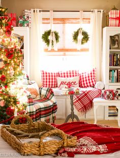 a living room decorated for christmas with red and white plaid pillows, wreaths and garland on the windowsill