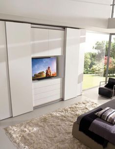 a bedroom with white walls and carpeted flooring has a flat screen tv on the wall