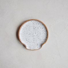 a white and brown plate sitting on top of a gray table next to a wall