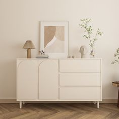 a white cabinet sitting next to a lamp on top of a hard wood floored floor