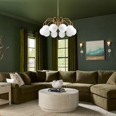 a living room with green walls and white furniture on the floor, including a large sectional couch