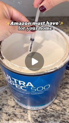 someone using a spatula to paint a blue bucket with white lettering on it and the words amazon must have for your home