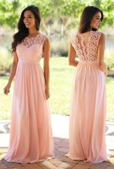 two women in pink dresses standing next to each other on a brick walkway with grass and trees behind them