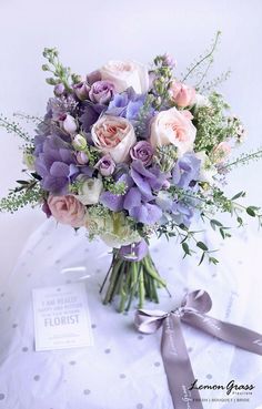 a bouquet of flowers sitting on top of a table next to a card and ribbon