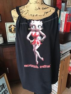 "Vintage 1980s *Betty Boop* Tee Shirt that was re-purposed into a sleeveless Tunic Tank Top. The Black color is a DARKER Black than how it shows up in pictures. Has some stretch. The strap around the top is a long fringed piece of sewing trim. Freshly laundered. CONDITION: Has 6 small spots on the lower front of the shirt (SEE PIX). Sold As Is! MEASURES: Bust~48\"------>50\" Hips~48\"--->52\" Top strap to bottom~28\" **WE APOLOGIZE~BUT WE CAN NO LONGER SHIP TO ITALY OR SPAIN. WE HAVE INCURRED TOO MANY ISSUES WITH SHIPPING. PACKAGES GOING MISSING..DAMAGED...ETC. IF ORDERS COME IN FROM ITALY OR SPAIN, WE WILL HAVE TO CANCEL THEM AND REFUND YOUR MONEY. SORRY FOR THIS INCONVENIENCE. BUT WE CAN NO LONGER DEAL WITH THESE ISSUES. THANK YOU FOR UNDERSTANDING**" Betty Boop Pictures Vintage, Vintage Clothing Boutique, Tunic Tank Tops, Sleeveless Tunic, Sewing Trim, Beautiful Hats, Betty Boop, Sleeveless Tank, Shirt Top