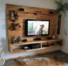 a flat screen tv sitting on top of a wooden wall mounted entertainment center next to a cow skin rug