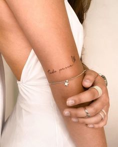 a woman wearing a white dress holding onto her arm with the word take peace tattooed on it