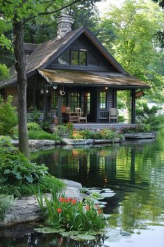 a small house sitting on top of a lush green hillside next to a lake with lily pads