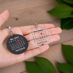 a person holding two key chains with a calendar printed on the front, and an acrylic key chain attached to them