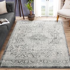 a living room with a gray couch and rug on the hardwood floor next to a window