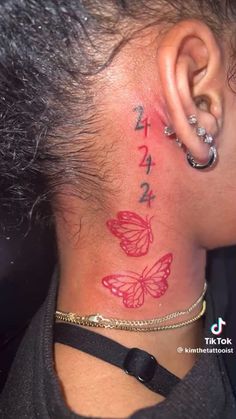 the back of a woman's neck with butterflies on it and numbers behind her ear