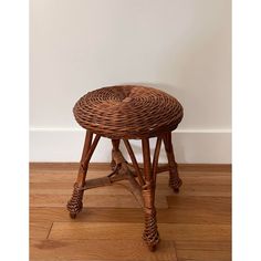 a wicker stool sitting on top of a hard wood floor next to a wall