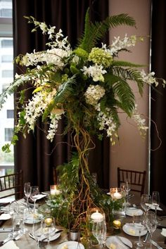 a tall vase filled with white flowers on top of a table