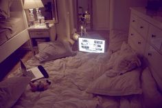 a laptop computer sitting on top of a bed in a room with white sheets and pillows