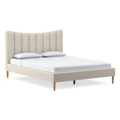 an upholstered bed with white sheets and pillows