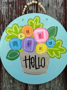 a painted sign that says hello with colorful flowers in a pot on the side of a wooden fence