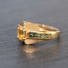 This stunning 14k yellow gold ring features an oval cut yellow sapphire prong set in the center with 4 princess cut green sapphires channel set on either side. Stone Significance:Sapphire is a stone that attracts abundance + blessings to those who wear it. It has been used to protect against negative energies, as well as calm the mind, strengthen intuition, and invite spiritual clarity. ⊹ 14k Yellow gold, Yellow Sapphire + Green Sapphire⊹ Stamp reads 14k ⊹ Excellent vintage, pre-owned condition⊹ Yellow Gold Sapphire Ring With Emerald Cut, Yellow Gold Multi-stone Emerald Cut Sapphire Ring, Heirloom Gold Sapphire Ring With Gemstone Accents, Emerald Cut Multi-stone Sapphire Ring In Yellow Gold, Gold Multi-stone Emerald Cut Sapphire Ring, Gold Princess Cut Birthstone Ring With Accent Stones, Gold Emerald Ring With Channel Set Emerald Cut, Gold Sapphire Ring With Emerald Cut And Gemstone Accents, Gold Emerald-cut Sapphire Ring With Gemstone Accents