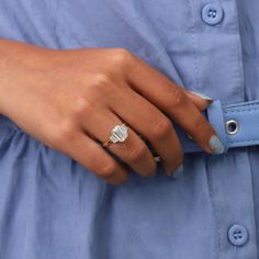 a woman's hand with a ring on her finger, wearing a blue shirt