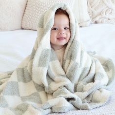 a little boy wrapped in a blanket on top of a bed