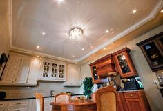 a dining room table and chairs in front of a chandelier above the kitchen counter