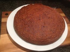 a round cake sitting on top of a white plate next to a wooden cutting board