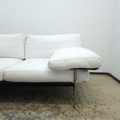 a white couch sitting on top of a wooden floor next to a rug and wall