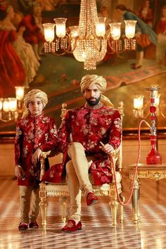 two people sitting on a chair in front of a chandelier