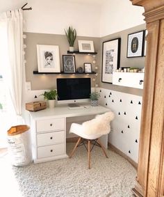 a white desk with a computer on top of it in a room filled with pictures