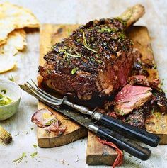 a large piece of meat sitting on top of a cutting board next to some bread