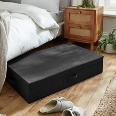 a pair of slippers sitting on the floor next to an open storage box in front of a bed