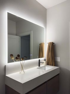 a bathroom with a sink, mirror and towels on the rack in front of it