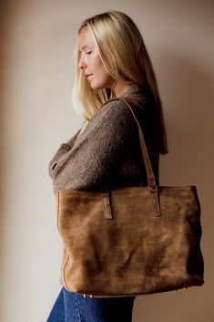 Introducing our Suede Tote: The Perfect Blend of Style and Functionality I designed this bag out of a need for a way to carry my laptop as the weather changes. I fell in love with this gorgeous caramel suede when I visited the tannery in Nairobi last year and knew it would be so perfect for fall. It's the perfect brown that feels golden and rich against black and is the perfect neutral tying together the color tones in your fall wardrobe. I like to wear my Sling Bag even while carrying The Tote