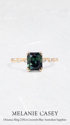 an emerald colored ring with diamonds on the sides and side stones in gold plated setting