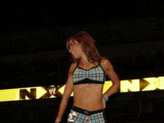 a woman standing on top of a stage wearing a plaid skirt and high waisted shorts