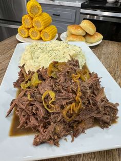 a white plate topped with roast beef and mashed potatoes next to corn on the cob