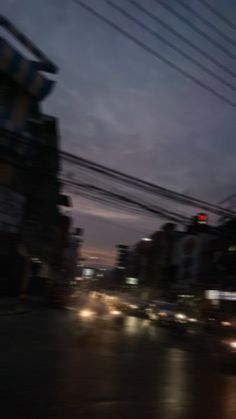 blurry image of city street at night with traffic lights and power lines in the foreground