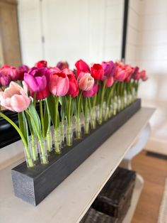 there are many pink and red tulips in vases on the counter top