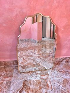 a mirror sitting on top of a marble floor next to a pink wall with stripes